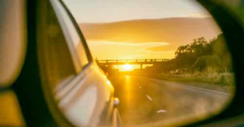 Road at sunset as seen from the car side mirror